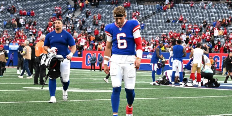 Giants quarterback Jaxson Dart (6) walking off the field after losing a football game.