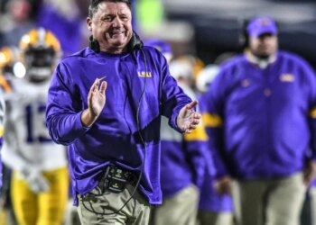 LSU coach Ed Orgeron smiles and claps during a game.