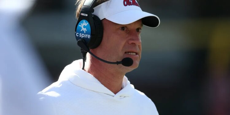 Lane Kiffin, head coach of the Mississippi Rebels, wears a white visor and a headset while looking on.