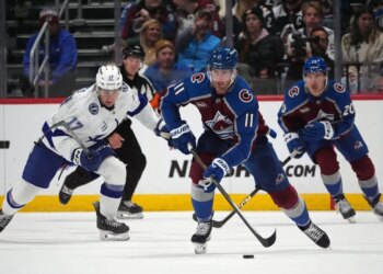 Colorado Avalanche center Brock Nelson (11) heads down the ice with the puck as center Ross Colton, back right, and Tampa Bay Lightning center Dominic James pursue in an NHL hockey game.