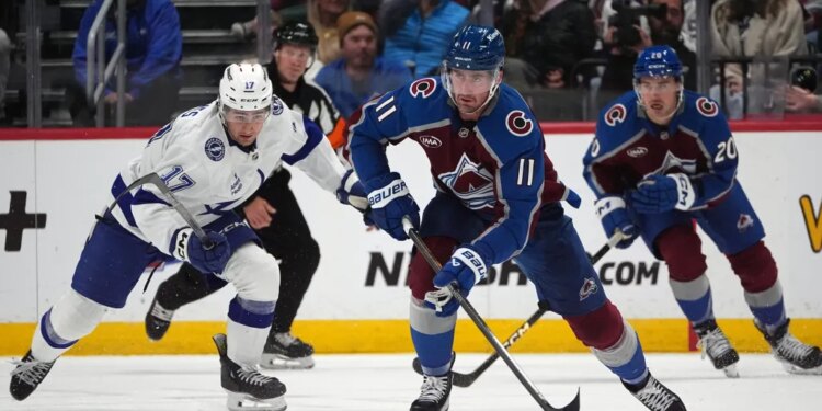 Colorado Avalanche center Brock Nelson (11) heads down the ice with the puck as center Ross Colton, back right, and Tampa Bay Lightning center Dominic James pursue in an NHL hockey game.