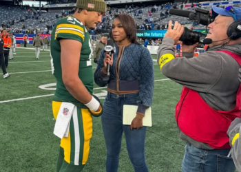 Green Bay Packers player Jordan Love being interviewed by a Fox reporter on the field.