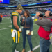 Green Bay Packers player Jordan Love being interviewed by a Fox reporter on the field.