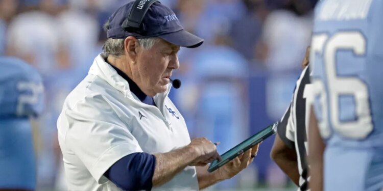 North Carolina head coach Bill Belichick checking his tablet during a football game.