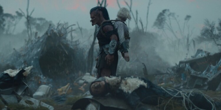 A Yautja alien with a humanoid robot missing her legs strapped to its back.