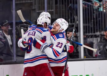 New York Rangers players Adam Fox (23) and J.T. Miller (8) celebrate a win against the Seattle Kraken.