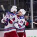 New York Rangers players Adam Fox (23) and J.T. Miller (8) celebrate a win against the Seattle Kraken.