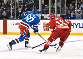 New York Rangers defenseman Scott Morrow (60) skates with the puck while defended by Detroit Red Wings center Andrew Copp (18).