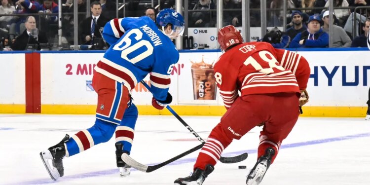 New York Rangers defenseman Scott Morrow (60) skates with the puck while defended by Detroit Red Wings center Andrew Copp (18).