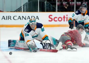 New York Sirens goaltender Kayle Osborne (82) watches the puck as Ottawa Charge's Brianne Jenner (19) slides along the ice.