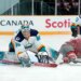 New York Sirens goaltender Kayle Osborne (82) watches the puck as Ottawa Charge's Brianne Jenner (19) slides along the ice.