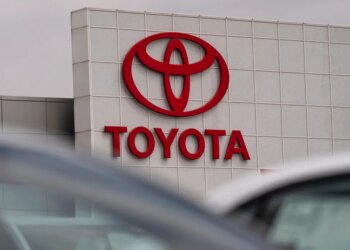 Red Toyota logo and name on the side of a dealership building.