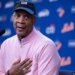 Darryl Strawberry speaking at a press conference, wearing a black cap, pink shirt, and championship ring.