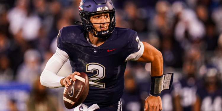 UConn quarterback holds a football.