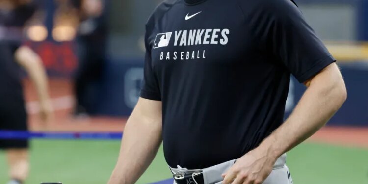 New York Yankees pitcher Gerrit Cole in a black Yankees t-shirt and hat, holding a black glove.