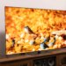 The LG G5 OLED TV on a wooden home theater credenza, displaying an image of small colorful birds.