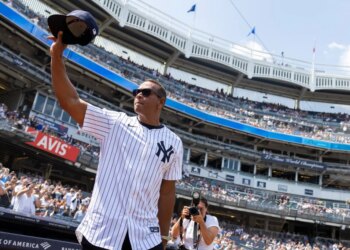 Alex Rodriguez salutes fans, holding his baseball cap in the air, during Old Timer’s Day.