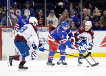 New York Rangers defenseman Braden Schneider (4) and Colorado Avalanche players Martin Necas (88) and Ross Colton (20) chase the puck in an ice hockey game.