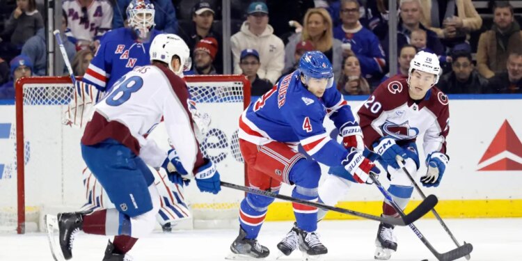 New York Rangers defenseman Braden Schneider (4) and Colorado Avalanche players Martin Necas (88) and Ross Colton (20) chase the puck in an ice hockey game.