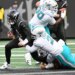 Jets quarterback Brady Cook (4) running with the ball as a Miami Dolphins player tackles him.