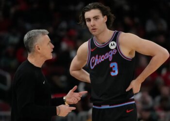 NBA coach Billy Donovan speaking with a player in a black Chicago Bulls jersey.
