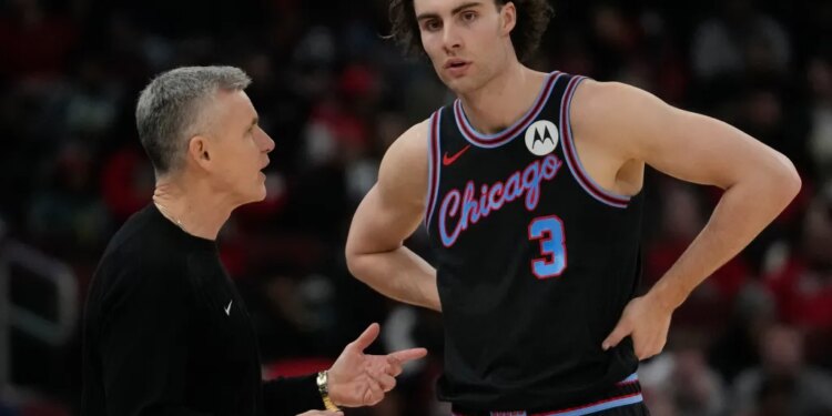 NBA coach Billy Donovan speaking with a player in a black Chicago Bulls jersey.