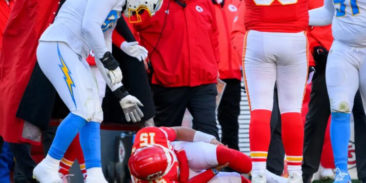 Kansas City Chiefs quarterback Patrick Mahomes (15) on the ground as Chargers defensive tackle Justin Eboigbe (92) and Chiefs head coach Andy Reid watch.