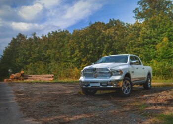 White Dodge RAM 1500 parked on a dirt road in a forest.