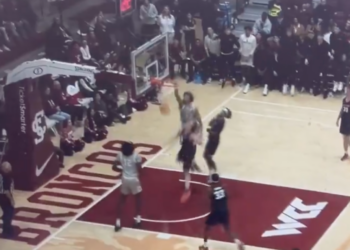 Basketball player in a gray jersey mid-dunk.