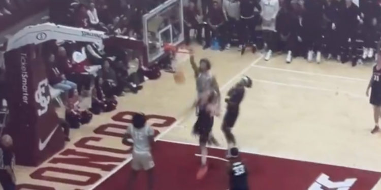Basketball player in a gray jersey mid-dunk.