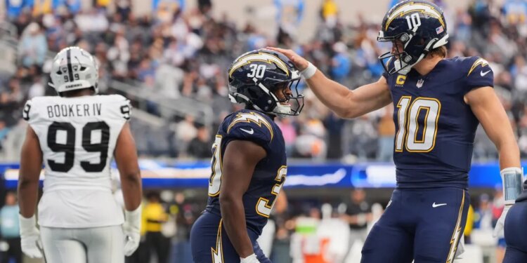Los Angeles Chargers running back Kimani Vidal (30) celebrates with quarterback Justin Herbert (10) after scoring a touchdown against the Las Vegas Raiders.