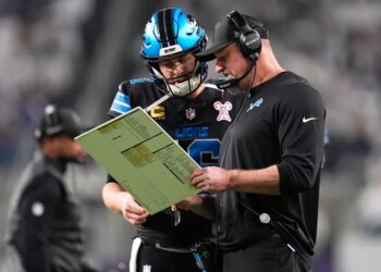 Detroit Lions quarterback Jared Goff, left, speaks with head coach Dan Campbell during the first half of an NFL football game against the Minnesota Vikings, Thursday, Dec. 25, 2025, in Minneapolis.
