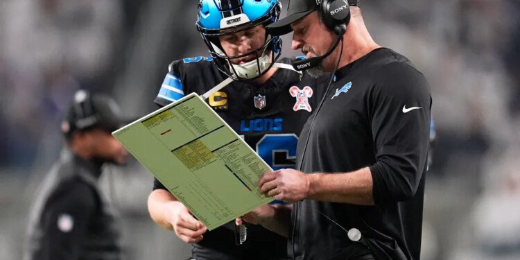 Detroit Lions quarterback Jared Goff, left, speaks with head coach Dan Campbell during the first half of an NFL football game against the Minnesota Vikings, Thursday, Dec. 25, 2025, in Minneapolis.