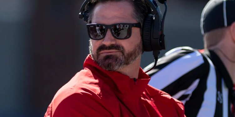 Louisiana head coach Michael Desormeaux wearing sunglasses and a headset, looking back at his bench.