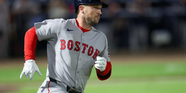 A Boston Red Sox player wearing a helmet and a grey uniform with "BOSTON" written in red on the front, running on a green baseball field.