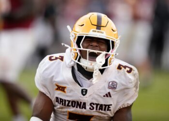Arizona State running back Raleek Brown shouts with his mouth open while wearing his football helmet and white uniform with "3" on the shoulder.