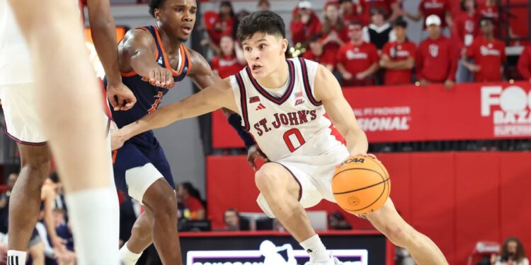 St. John's Red Storm player Dylan Darling dribbles the basketball while being guarded by a Bucknell Bison player.