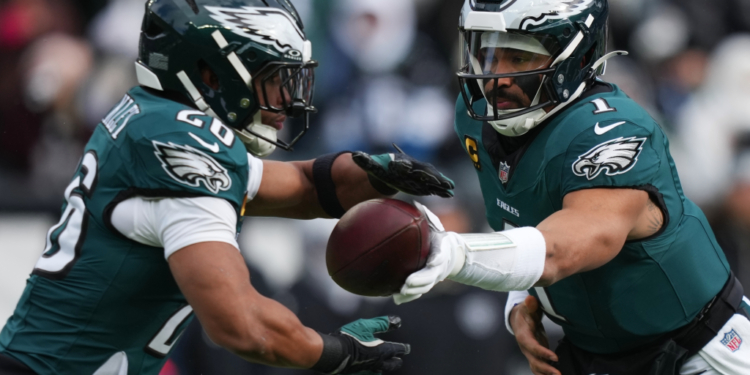 Two Eagles players, one wearing number 20 and the other number 1, in green uniforms, during a handoff.
