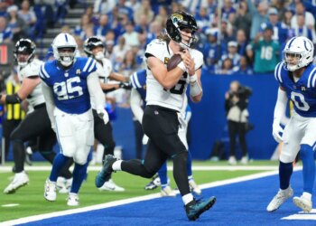 Jacksonville Jaguars quarterback Trevor Lawrence scores past Indianapolis Colts defensive tackle Adetomiwa Adebawore (95) and safety Camryn Bynum (0) during the second half of an NFL football game Sunday, Dec. 28, 2025.