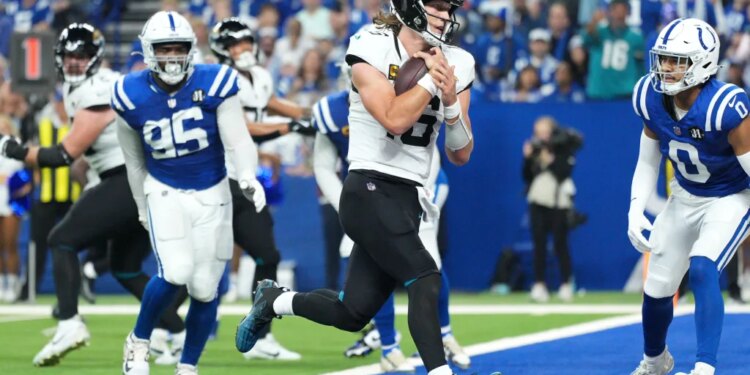 Jacksonville Jaguars quarterback Trevor Lawrence scores past Indianapolis Colts defensive tackle Adetomiwa Adebawore (95) and safety Camryn Bynum (0) during the second half of an NFL football game Sunday, Dec. 28, 2025.