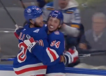 Two hockey players from the New York Rangers celebrating a goal.