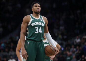 Giannis Antetokounmpo in a Milwaukee Bucks jersey holding a basketball.