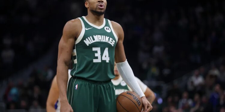 Giannis Antetokounmpo in a Milwaukee Bucks jersey holding a basketball.