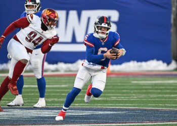 Quarterback Jaxson Dart #6 of the New York Giants runs with the ball while being pursued by a Washington Commanders player.