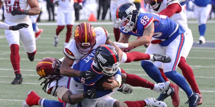 Quarterback Jaxson Dart of the New York Giants is tackled by safety Will Harris of the Washington Commanders.