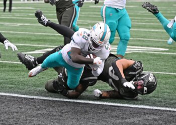 Dolphins running back De'Von Achane (28) runs the ball for a touchdown against a Jets player.
