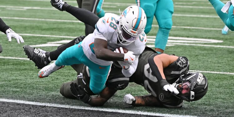 Dolphins running back De'Von Achane (28) runs the ball for a touchdown against a Jets player.