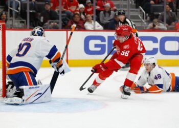 Detroit Red Wings center Emmitt Finnie (58) skates with the puck defended by New York Islanders defenseman Matthew Schaefer (48) in the second period at Little Caesars Arena.