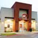 A Jack in the Box restaurant with a lit-up "Jack in the Box" sign on its red and beige facade.