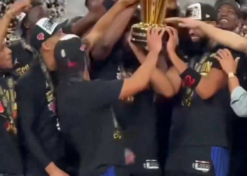 Josh Hart celebrating with his team while holding up a championship trophy.